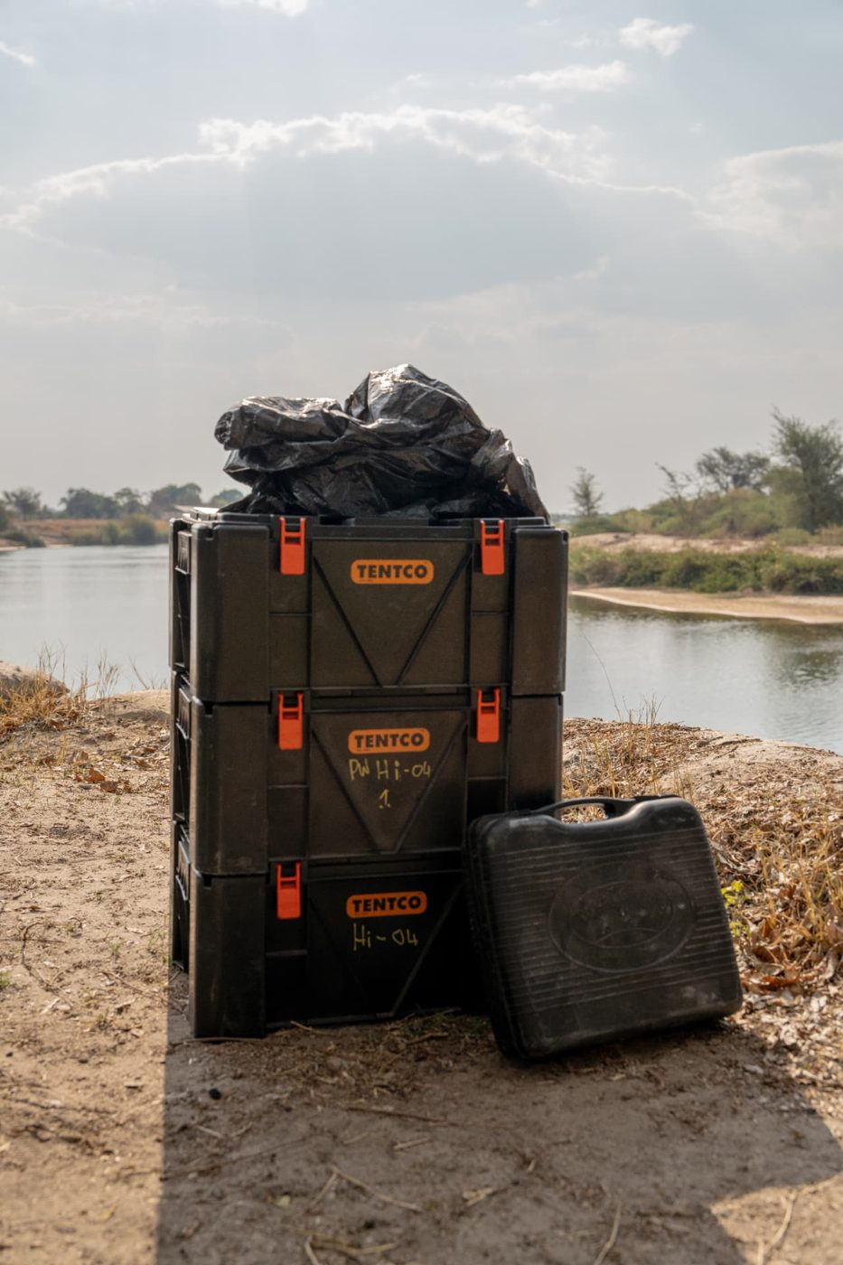 Stacked Tentco camping storage boxes and a tool case beside a river on a Namibia 4x4 self-drive trip