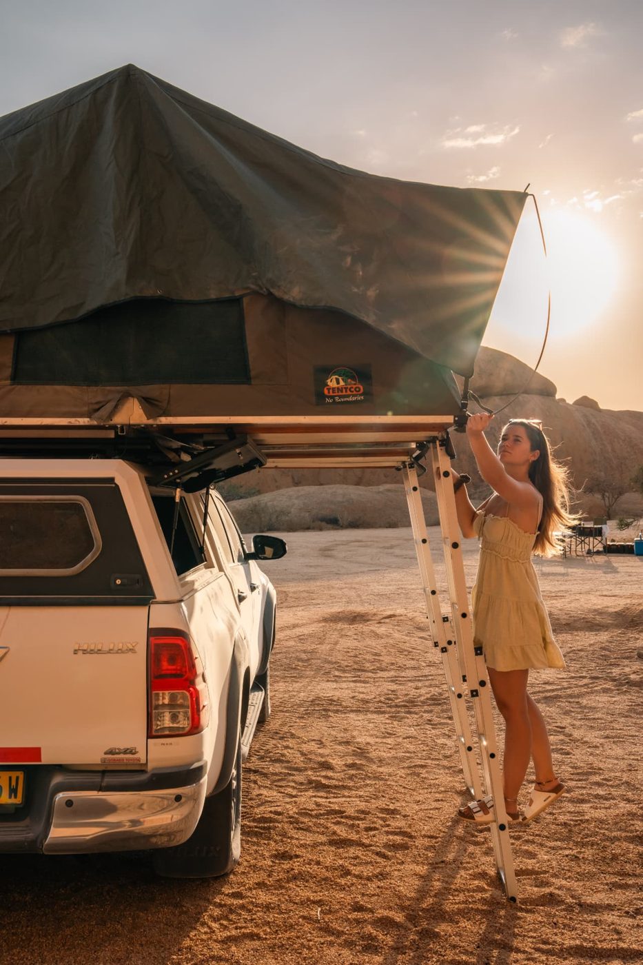 Traveller opening a Tentco rooftop tent on a Hilux at sunset near Spitzkoppe, Namibia