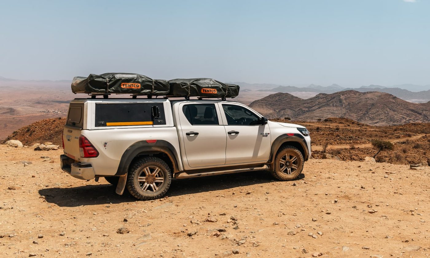 Toyota Hilux Double Cab 4x4 with two Tentco rooftop tents at a mountain viewpoint in Damaraland, Namibia