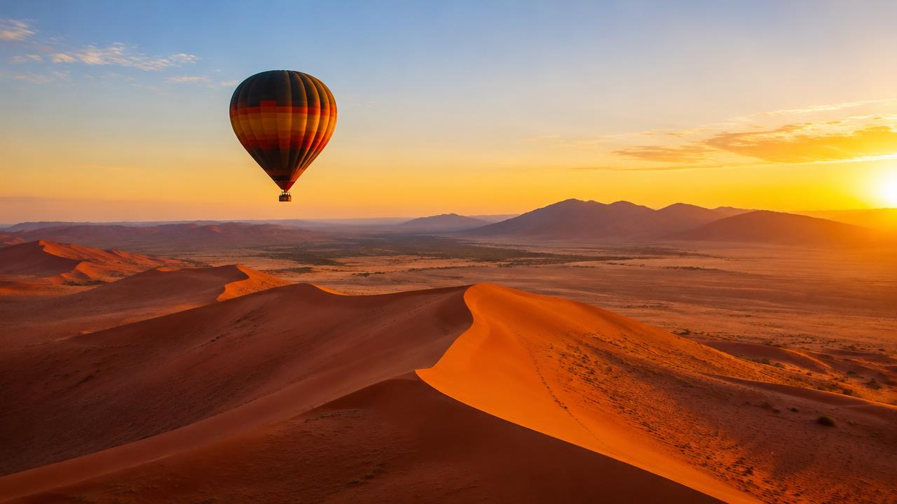 Hot air balloon over the red Sossusvlei dunes at sunrise, Namibia